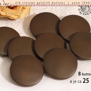 May include: Eight brown, round galalith buttons, each approximately 2.5 cm in diameter, are displayed. The image includes text indicating they are vintage from the 1940s-60s. The buttons are arranged on a white surface.