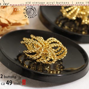 May include: Two vintage black acrylic buttons, each with a gold-coloured twisted rope design. The buttons are approximately 4.9 cm in diameter. The text on the image reads "old vintage acryl buttons | anno 1950/60".