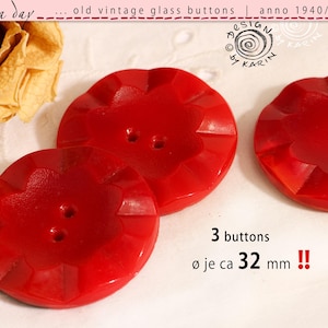 May include: Three bright red vintage glass buttons with a faceted, star-like floral shape and two centre holes. Each button measures approximately 32 mm in diameter. The text on the image reads: rosa day, old vintage glass buttons, anno 1940/50/60, design by karin, 3 buttons, ø je ca 32 mm.