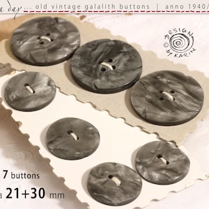 May include: Seven vintage grey galalith buttons with a marbled effect, ranging from 21 to 30 mm in diameter. The buttons are arranged on a decorative card. The text "rosa day" and "DESIGN by KARIN" are visible.