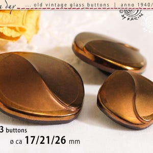 Könnte beinhalten: Drei alte Glas Knöpfe in Braun- und Kupfertönen. Die Knöpfe haben ein einzigartiges, geschwungenes Design und messen ca. 17, 21 und 26 mm im Durchmesser. Das Bild enthält den Text "3 buttons" und "Ø ca 17/21/26 mm."