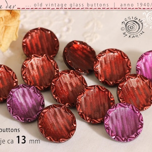 Op de afbeelding: Een verzameling van twaalf vintage glazen knopen in rood- en paars tinten. Elke knoop heeft een getextureerd, geribbeld patroon en een geschulpte rand. De knopen zijn ongeveer 13 mm in diameter. De tekst op de afbeelding luidt "old vintage glass buttons | anno 1940/50/60".