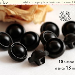 Könnte beinhalten: Zehn schwarze Glasknöpfe mit einem erhabenen Mittelteil und einem silbernen Rand. Die Knöpfe haben einen Durchmesser von etwa 13 mm. Ø je ca 13 mm