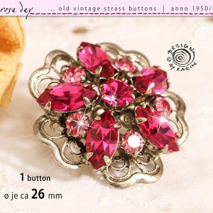 May include: Vintage silver-toned button with a floral design, adorned with vibrant pink strass crystals. The button, approximately 1 inch in diameter, features a central cluster of larger stones surrounded by smaller ones. The text on the image says "rosa day" and "old vintage strass buttons | anno 1950/60".