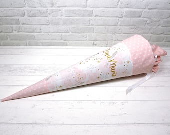 May include: A pink and white fabric cone with gold glitter and stars. The cone has the name "Lina Marie" written on it in gold lettering.