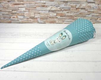 May include: A teal blue fabric cone with white stars and a white circle with a bunny illustration and the text "Tabelleig" and "Geburtstag 2023".