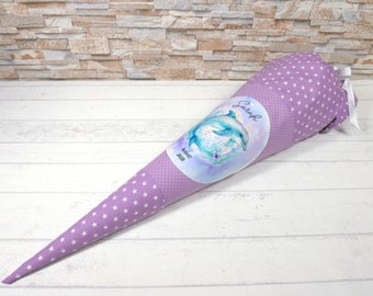 May include: Purple fabric cone with white stars and a label featuring two dolphins and the name "Sarah" with the date "August 2023".