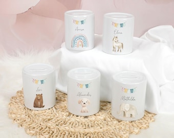 May include: Five white ceramic coin banks with illustrations of a rainbow, horse, bear, puppy, and elephant. Each bank has a name printed on it and a slot for coins on top. The banks are decorated with colorful bunting.
