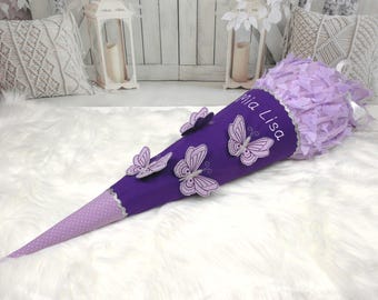 May include: Purple school cone with white polka dots and a white ribbon. The cone has a name, "Mia Lisa", embroidered on it. There are five purple butterflies with white accents on the cone.