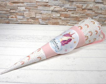 May include: A pink and white cone-shaped party favor with a rainbow and polka dot pattern. The cone has a label with a unicorn illustration and the name "Marlene" written on it.