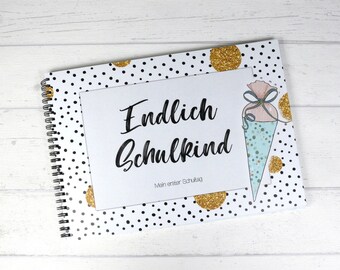 May include: A black and white polka dot notebook with gold glitter accents. The cover features the text "Endlich Schulkind" and "Mein erster Schultag".