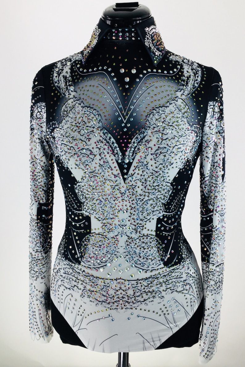 May include: A black and white long-sleeved shirt with a rhinestone design. The shirt has a v-neck and a fitted silhouette.