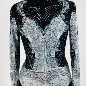 May include: A black and white long-sleeved shirt with a rhinestone design. The shirt has a high neck and a fitted silhouette.