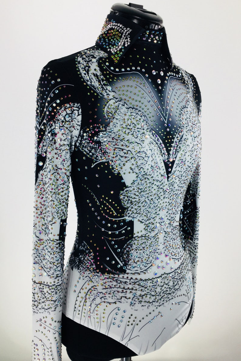 May include: A black and white long-sleeved shirt with a rhinestone design. The shirt has a high collar and a fitted silhouette.