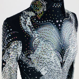 May include: Black and white long-sleeved shirt with a rhinestone design. The shirt has a collar and a button-up front.