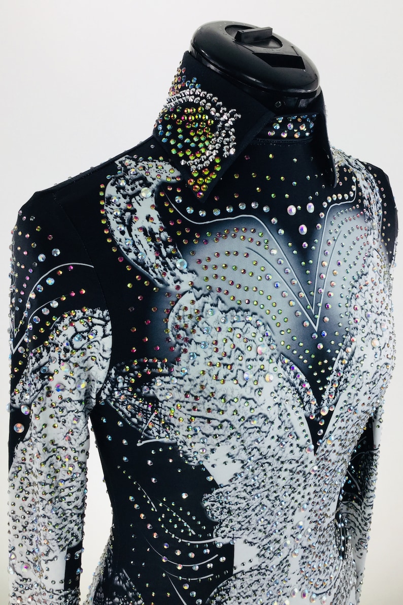 May include: Black and white long-sleeved shirt with a rhinestone design. The shirt has a collar and a button-up front.