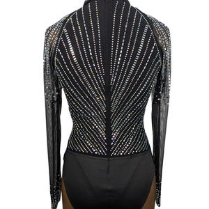 May include: Black long-sleeved bodysuit with a high neckline and a geometric pattern of iridescent rhinestones on the front and back.