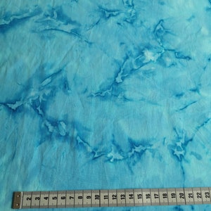 Könnte beinhalten: Nahaufnahme eines türkisfarbenen Stoffes mit Marmormuster. Ein Maßband liegt auf dem Stoff und zeigt Maße von 2 bis 23 Zoll.