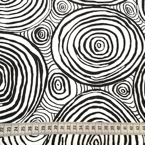 Könnte beinhalten: Schwarz-weißes Stoffmuster mit sich wiederholenden konzentrischen Kreisen. Der Stoff wird mit einem Maßband gemessen, das von 22 bis 44 Zoll reicht.