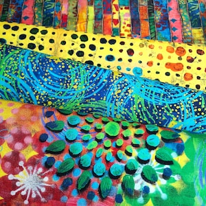 Könnte beinhalten: Ein Stapel bunter Stoffrollen mit verschiedenen Mustern. Die oberste Rolle zeigt vertikale Streifen in Rot, Gelb, Blau und Grün. Andere Rollen zeigen gelbe Punkte, blaue Wirbel und ein Blumendesign mit grünen Blättern.