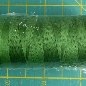 K&ouml;nnte beinhalten: Eine Spule gr&uuml;nen Garns, verpackt in Plastik mit einem roten Etikett mit der Aufschrift "5018".