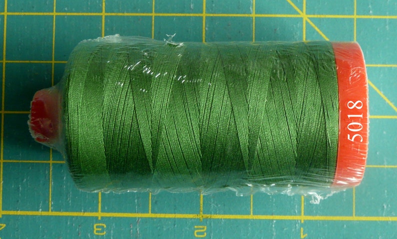 K&ouml;nnte beinhalten: Eine Spule gr&uuml;nen Garns, verpackt in Plastik mit einem roten Etikett mit der Aufschrift "5018".