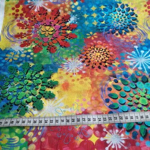 Könnte beinhalten: Bunter Stoff mit einem lebendigen, abstrakten Blumenmuster. Das Muster zeigt große, stilisierte Blumen in Rot-, Orange-, Gelb-, Blau- und Grüntönen. Ein Lineal liegt unten mit Messungen von 38 bis 104 cm.