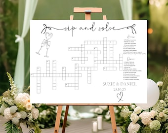 May include: A white sign with the text "Sip and Solve" and a crossword puzzle. The crossword puzzle has clues related to a wedding. The sign also includes the names "Suzie & Daniel" and the date "28.10.25".