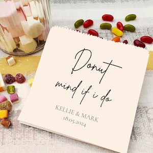 May include: A white favour bag with the text "Donut mind if I do" in black script font. Below the text is "Kellie & Mark" and the date "18.05.2024".