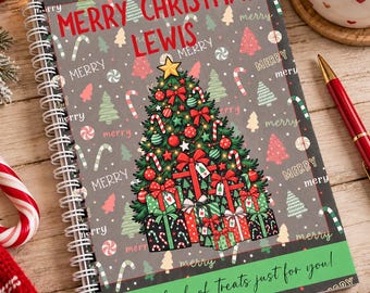 May include: A spiral-bound notebook with a gray cover featuring a repeating pattern of Christmas trees, candy canes, and the word merry. The cover displays a large decorated Christmas tree, gifts, and the text MERRY CHRISTMAS LEWIS and A little book of Treats just for you!