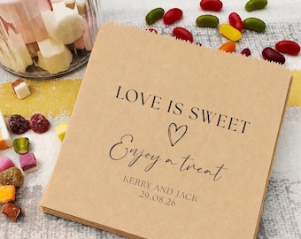 May include: A square brown paper bag featuring black printed text that reads LOVE IS SWEET, a heart icon, Enjoy a treat, KERRY AND JACK, and the date 29.08.26. The bag is surrounded by various colorful jelly bean candies and a glass jar.