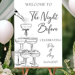 May include: A white rectangular wedding welcome sign featuring black line art of a champagne bottle pouring into a stacked tower of six coupe glasses. The text reads: WELCOME TO The Night Before CELEBRATING Pete & Amy 24.04.2025 in black font.