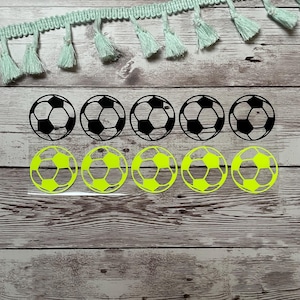 Può includere: Due file di adesivi di palloni da calcio. La fila superiore ha cinque palloni da calcio in bianco e nero. La fila inferiore ha cinque palloni da calcio di colore verde neon.