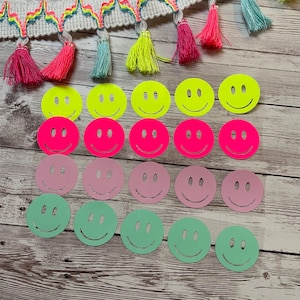 Peut inclure: Une collection de 20 autocollants smiley de différentes couleurs, dont le jaune néon, le rose et le vert. Les autocollants sont disposés en quatre rangées de cinq autocollants chacune.