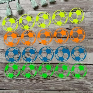 Könnte beinhalten: Ein Set mit 18 Fußball-Aufklebern in drei Farben: Neongrün, Orange und Blau. Die Aufkleber sind in drei Reihen mit jeweils sechs Aufklebern angeordnet, wobei jede Reihe eine andere Farbe hat.