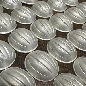 May include: A white ceramic mug with a black handle and the text "But First, Coffee" in a black, handwritten-style font. The mug is on a white surface.