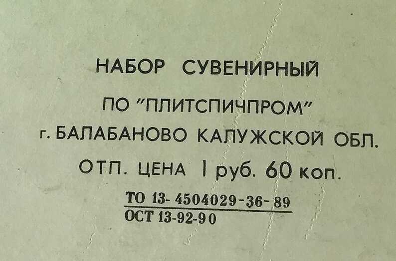 May include: A black and white label with the text "НАБОР СУВЕНИРНЫЙ ПО "ПЛИТСПИЧПРОМ" г. БАЛАБАНОВО КАЛУЖСКОЙ ОБЛ. ОТП. ЦЕНА 1 руб. 60 коп. ТО 13-4504029-36-89 ОСТ 13-92-90"