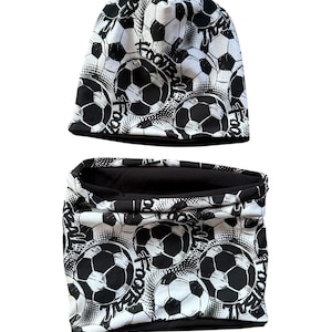Könnte beinhalten: Ein schwarzes und weißes Mützen- und Halstuch-Set. Das Set zeigt ein sich wiederholendes Muster aus Fußbällen und dem Wort "FOOTBALL". Die Mütze ist im Stil einer Skullcap gehalten, und das Halstuch hat eine Schlauchform.