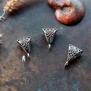 Könnte beinhalten: Drei silberne dreieckige Metall-Endkappen mit komplizierten keltischen Knotendesigns. Die Endkappen haben eine Schlaufe unten zum Anbringen an Schmuck oder anderen Bastelarbeiten.