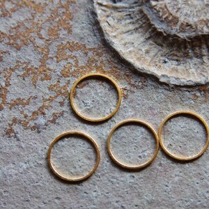 Könnte beinhalten: Vier goldfarbene Metallringe in verschiedenen Größen auf einer strukturierten grauen Oberfläche.