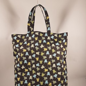 Könnte beinhalten: Eine schwarze Tragetasche mit einem sich wiederholenden Muster aus grünen, blauen und gelben Fröschen. Die Tasche hat zwei Henkel.