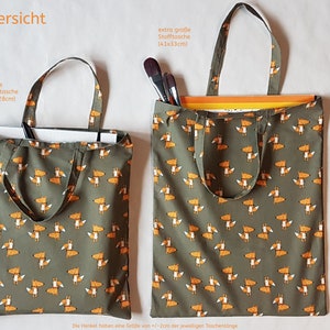 Op de afbeelding: Vier stoffen draagtassen in verschillende maten, elk met een herhaald patroon van oranje vossen op een gedempte groene achtergrond. De tassen omvatten een kleine tas, een middelgrote tas, een grote tas en een trekkoordtas.