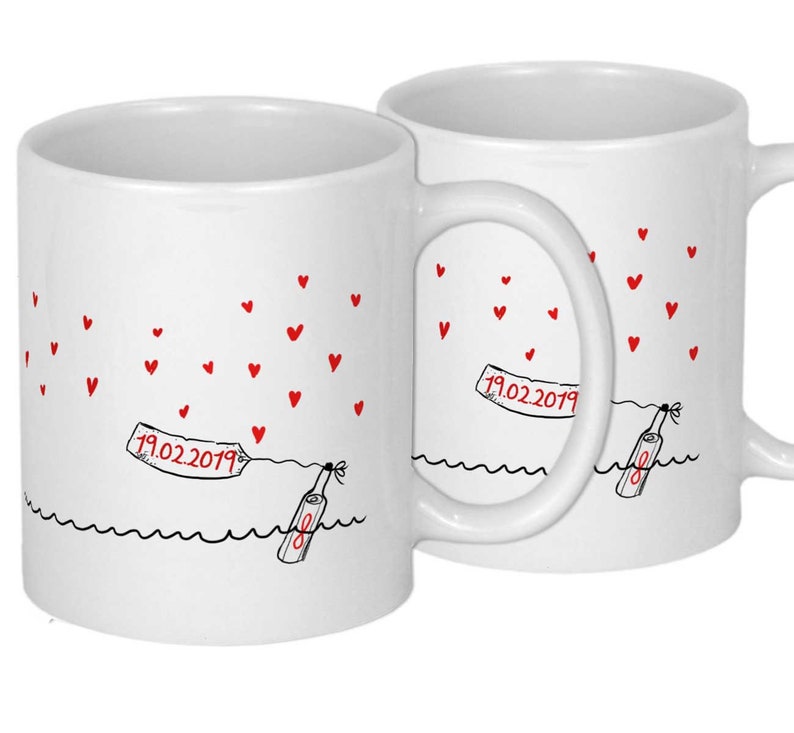 Pu&ograve; includere: Due tazze in ceramica bianca con manici neri. Le tazze presentano un'illustrazione in bianco e nero di una bottiglia con un messaggio al suo interno, che galleggia su una linea ondulata. Il messaggio sulla bottiglia dice "19.02.2019". Cuori rossi sono sparsi intorno alla bottiglia.