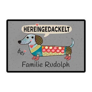 May include: A decorative doormat featuring a cartoon dachshund with a colorful patchwork design. The dog has a speech bubble with the German text "HEREINGEDACKELT" and the words "Familie Rudolph" below.