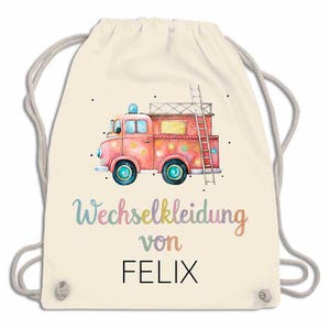 May include: A cream-colored drawstring backpack featuring a watercolor illustration of a pink fire truck with a ladder. The text "Wechselkleidung von FELIX" is written in colorful script below the truck. The bag has gray drawstrings.