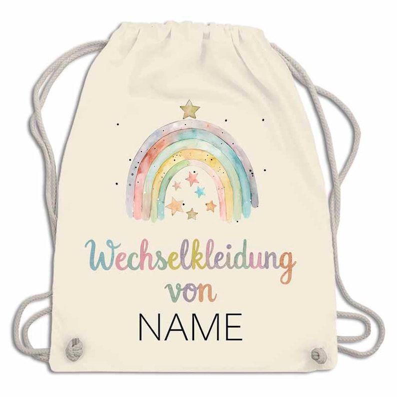 May include: A cream-colored drawstring backpack featuring a watercolor rainbow design with stars and the text "Wechselkleidung von NAME" in pastel colors. The bag has gray drawstrings.