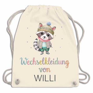 May include: Cream-colored drawstring backpack featuring a cartoon raccoon wearing a hat, scarf, jacket, and pants. The text "Wechselkleidung von Willi" is written in colorful script below the raccoon.