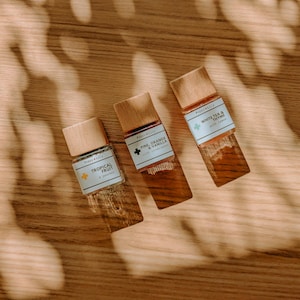 以下が含まれることがあります： コルク栓とラベルが付いた小さな木製のボトルが3本。ラベルは白地に黒文字で、緑色のアクセントが付けられています。ボトルには、トロピカルフルーツ、パイン、オレンジ＆バニラ、ホワイトティー＆タイムの香りがするエッセンシャルオイルが入っています。