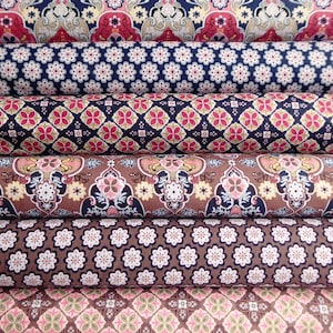 May include: Five rolls of fabric with different patterned designs. The patterns are all in shades of brown, pink, blue, and cream. The fabric is folded and rolled up.