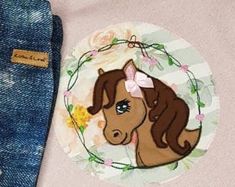 May include: Pink sweatshirt with a brown horse applique in a circle with floral accents. The sweatshirt has a high-low hemline and a white ribbed trim. The text "Rosa & Lina" is visible in the top right corner of the image.